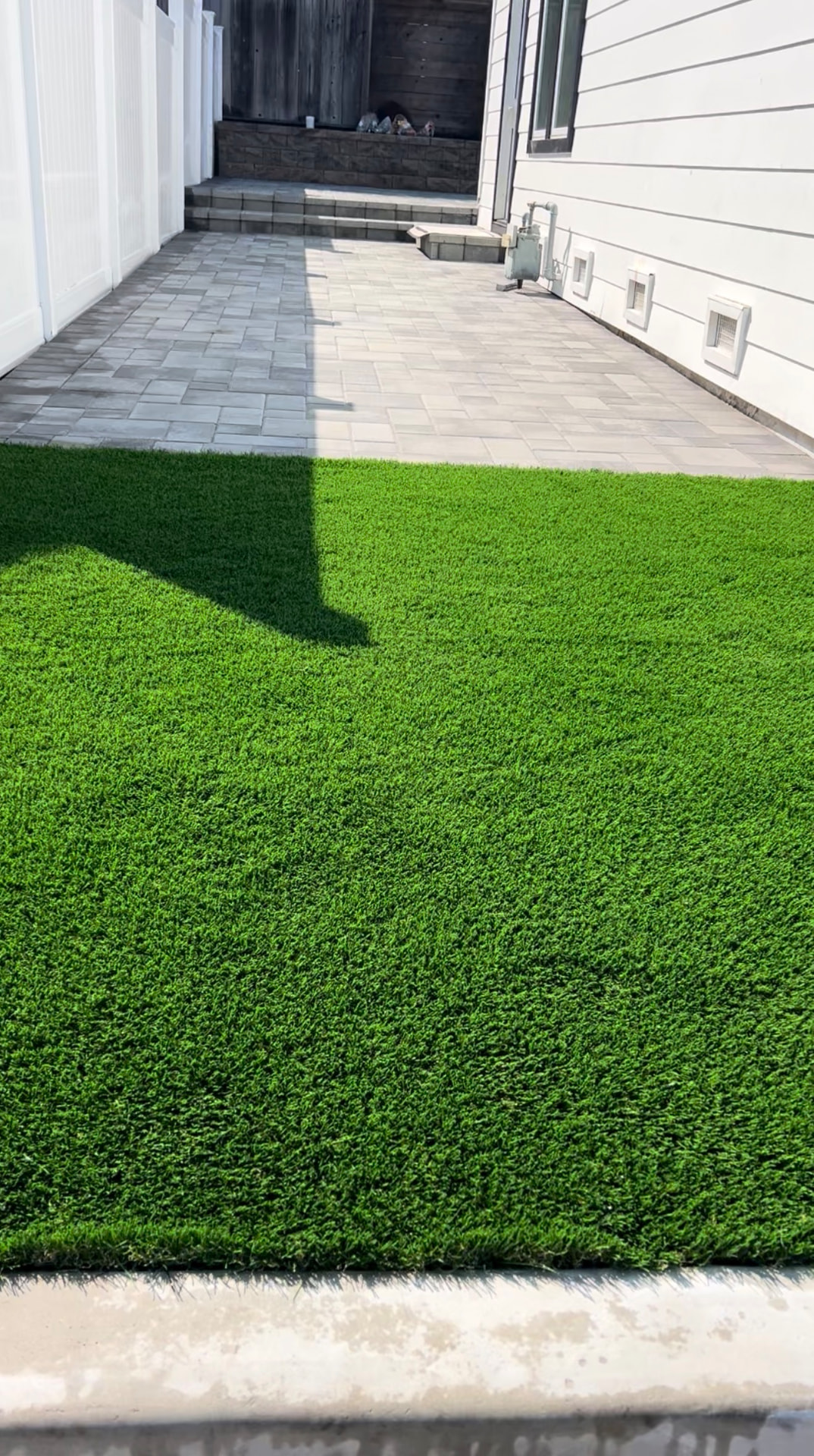 Side-yard artificial turf meeting a paver patio