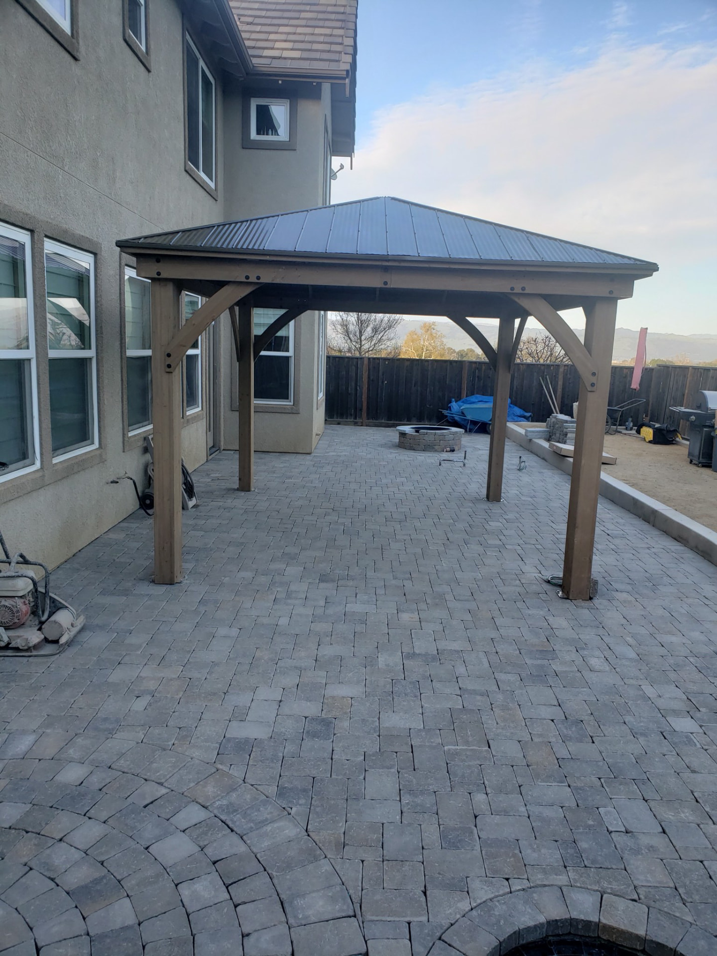 Paver patio with a timber gazebo and stone fire pit