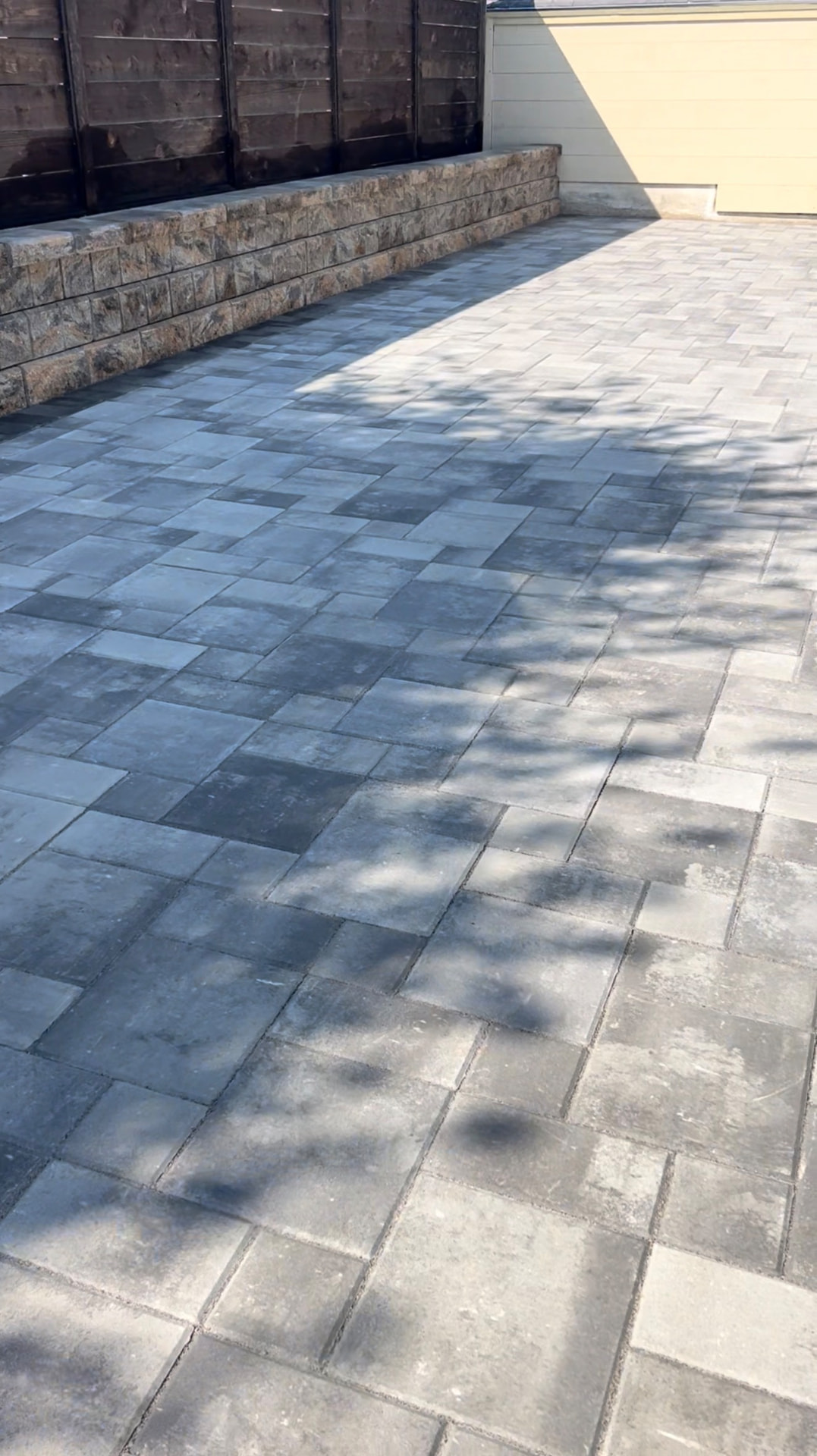 Paver courtyard beside a capped block retaining wall