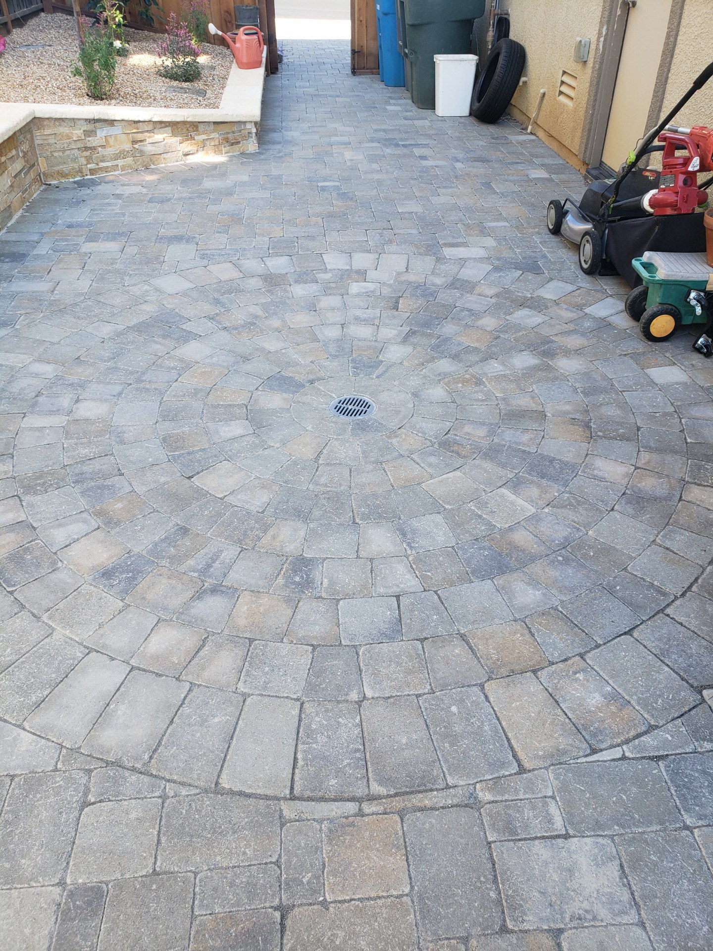 Circular paver pattern with a capped stone planter wall