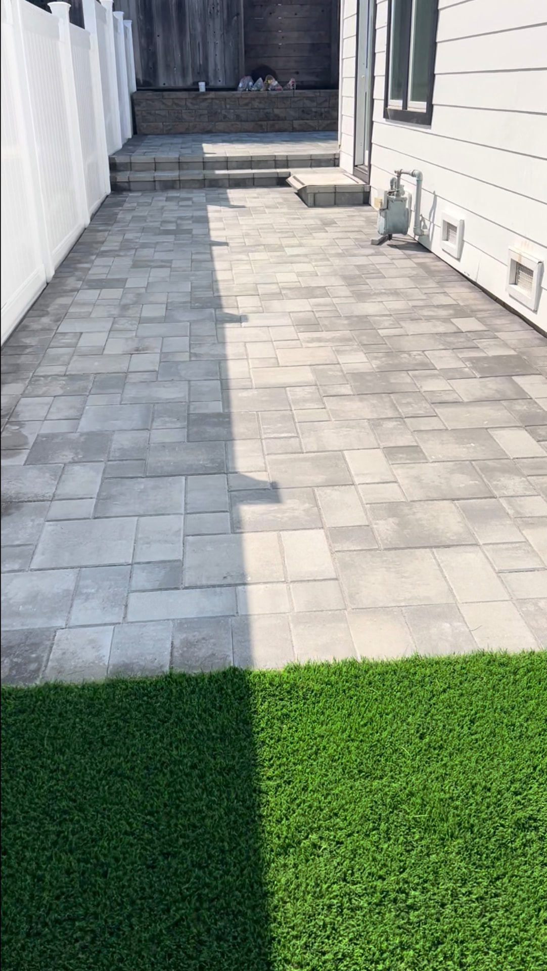 Side-yard paver patio with steps and a block retaining wall